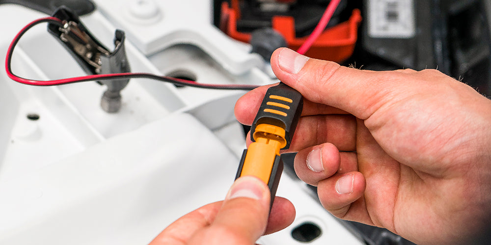 Hands connecting a yellow and black power clamp for campervan or off-grid electrical setup