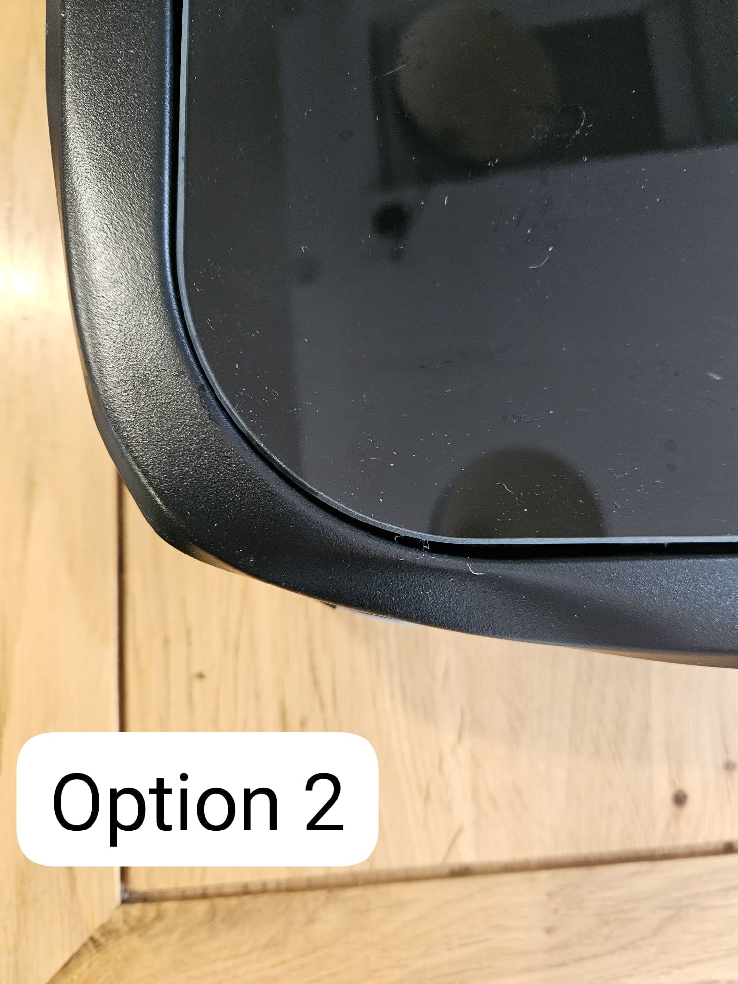 Close-up of a black plastic campervan window or hatch corner on a wooden surface, labeled Option 2.